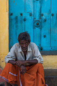 Portrait of man sitting against door