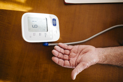 Hand of senior man using blood pressure gauge, close-up