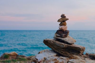 Stack of pebbles on beach against sky