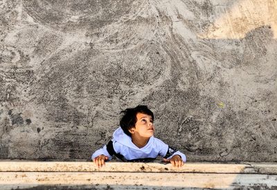 Full length of kid boy child sitting against wall