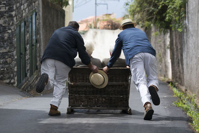 Rear view of men playing on street in city