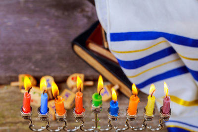 High angle close-up of lit colorful candles on wooden table