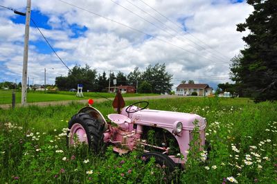 Abandoned vehicle on landscape against clouds