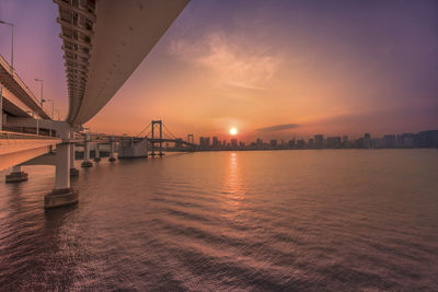 Bridge over sea against sky during sunset