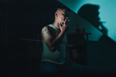 Young man smoking while sitting on floor