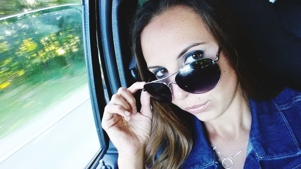 PORTRAIT OF WOMAN WEARING SUNGLASSES IN CAR