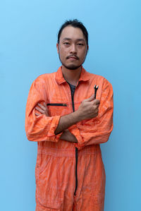 Portrait of young man standing against blue background