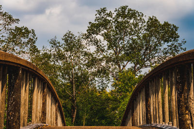 Low angle view of bridge amidst trees in forest against sky