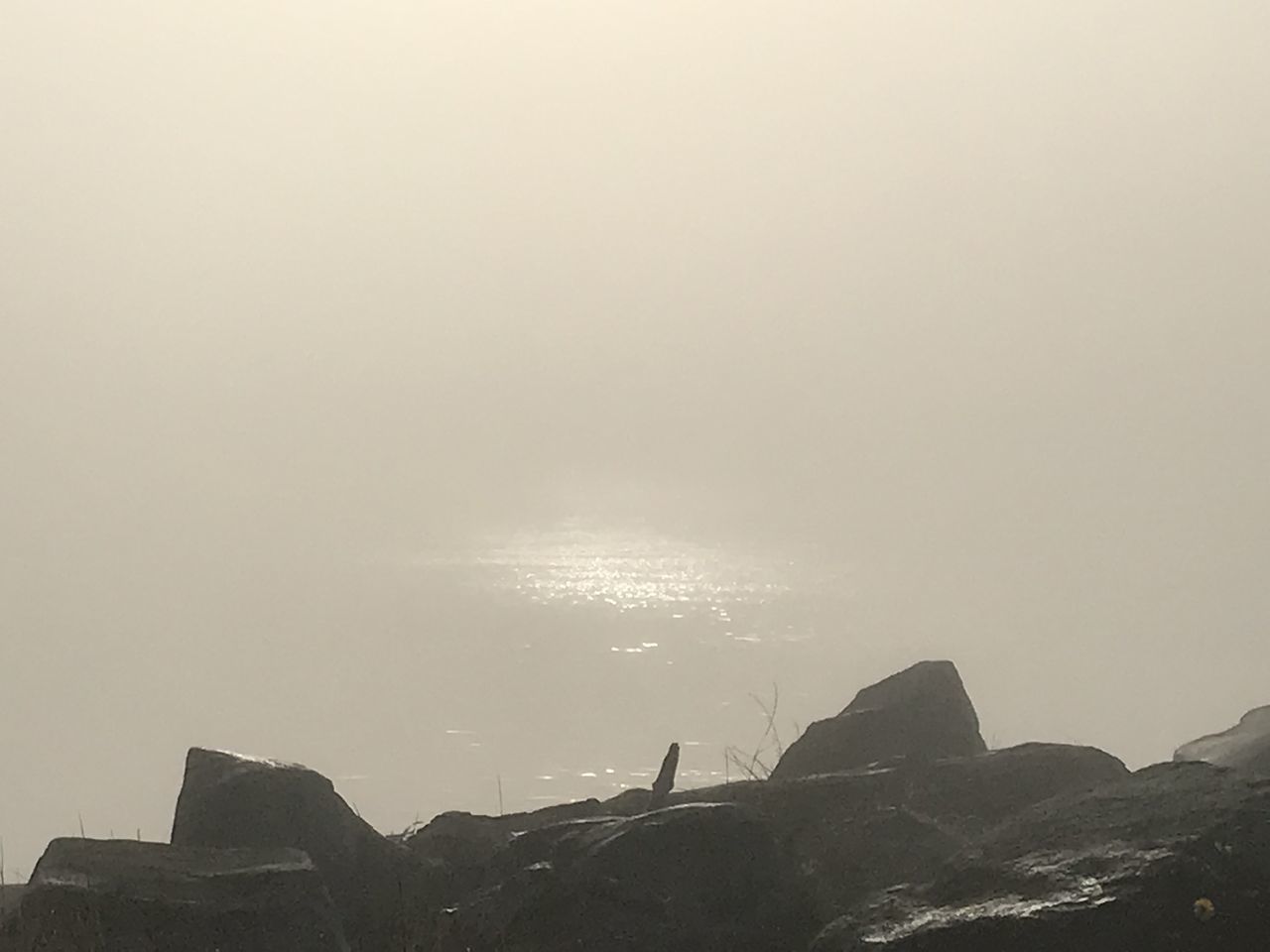 PEOPLE STANDING ON ROCK BY SEA AGAINST SKY DURING SUNRISE