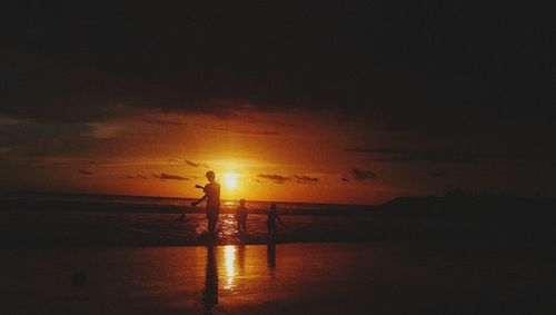 Silhouette man standing by sea against sky during sunset