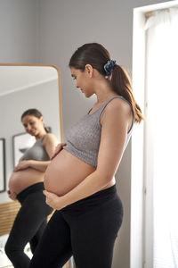 Pregnant woman standing in front of mirror