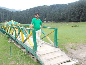 Full length of man standing on railing against sky