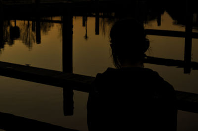 Reflection of silhouette woman in water against sky