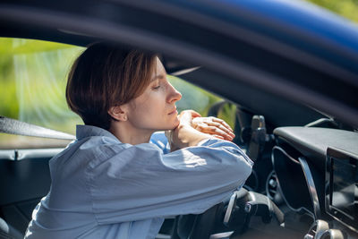 Side view of young woman using mobile phone while sitting in car