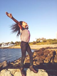 Full length of girl standing on rock against sky