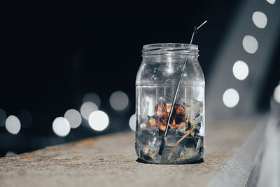 Close-up of glass jar on table against black background