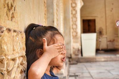 Girl covering eyes with hands in corridor