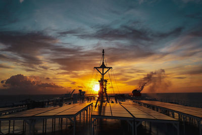 Silhouette pier over sea against sky during sunset