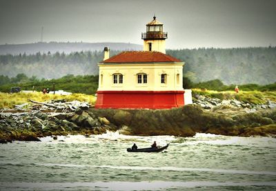 Lighthouse on beach against sky