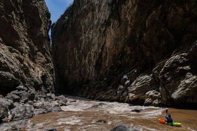 High angle view of man kayaking on river against rock formations