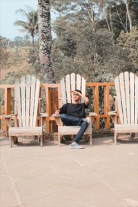 Portrait of man sitting on chair against trees