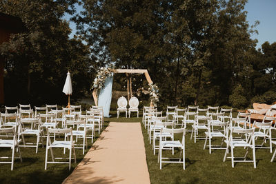 Wedding reception with empty chairs against trees