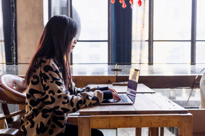 Portrait of young woman sitting on table in cafe