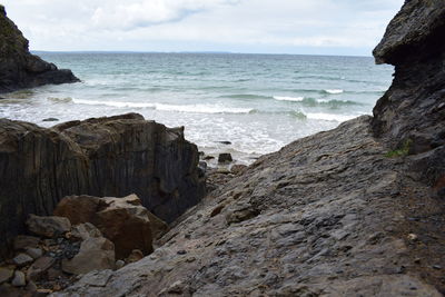 Scenic view of sea by cliff against sky