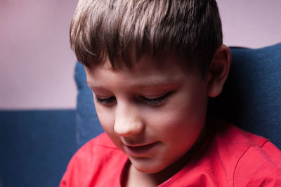 Close-up of boy looking down while sitting on sofa