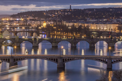 Illuminated bridge over river in city