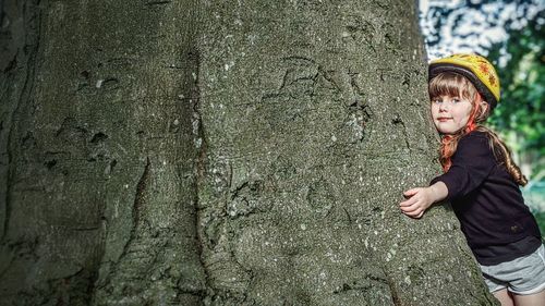 Portrait of boy standing on tree trunk