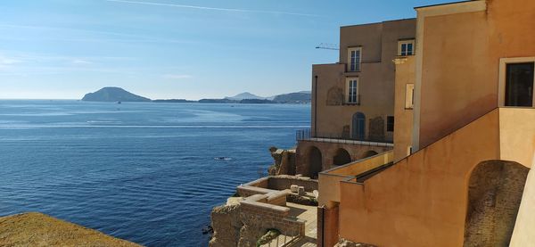 Buildings by sea against blue sky