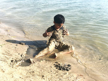 Full length of boy sitting at beach