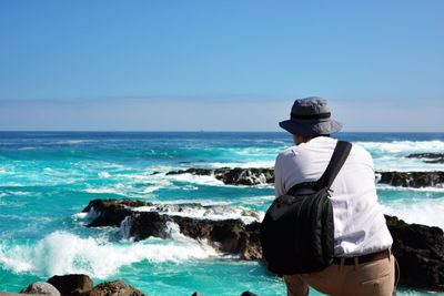 Rear view of man standing against sea