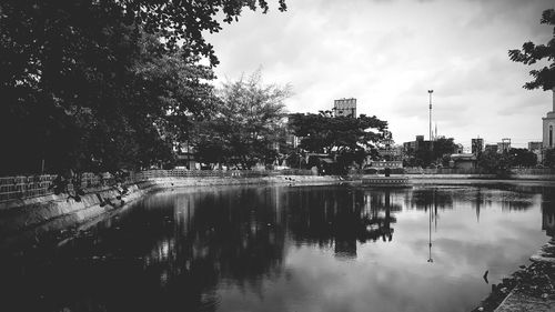 Reflection of buildings and trees in lake against sky