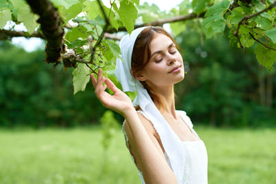 Portrait of young woman standing against plants