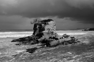 Rock formation on beach against sky