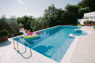 People relaxing by swimming pool in yard against sky