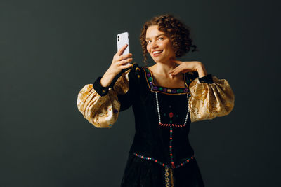 Young woman using mobile phone against black background