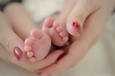 Cropped hands of mother holding boy legs at home