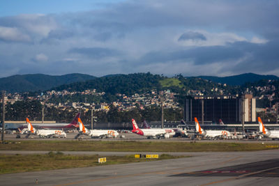 Airplane on airport runway against sky in city