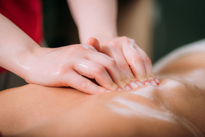 Massaging with massage oil, hands of a female massage therapist massaging a female client