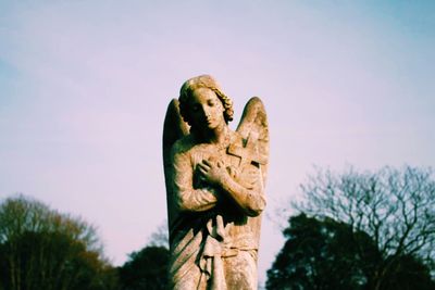 Angel statue with cross against sky