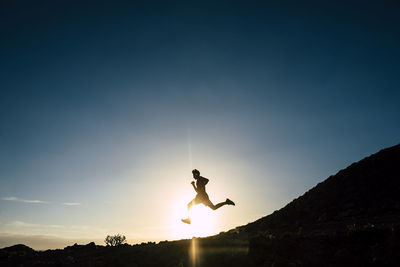 Silhouette man jumping against sky during sunset