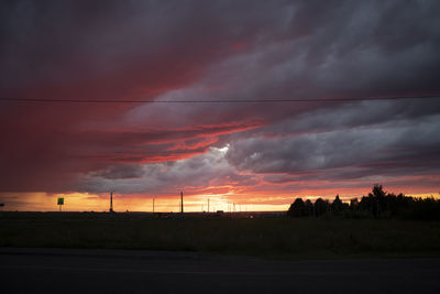 Scenic view of dramatic sky over field during sunset