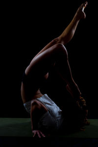 Young woman sitting against black background