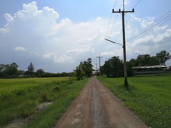 Road amidst field against sky