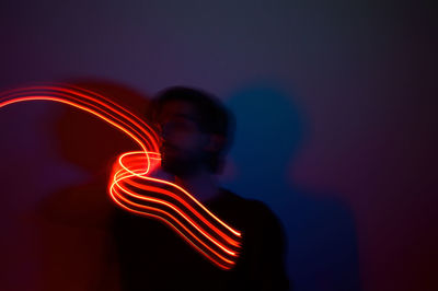 Close-up of man with illuminated lights against wall