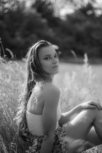 Portrait of young woman with dreamy eyes sitting in high grass 