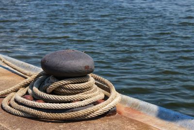 Close-up of rope tied on stack of sea